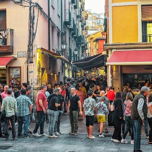 A group of people stood in a square with Spanish tapas bars on either side.