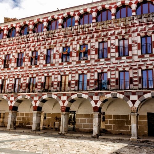 A red and white brick building with arches in Badajoz, Spain