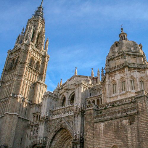 Toledo Cathedral in Spain, showcasing its stunning Gothic architecture and intricate details against a clear blue sky.