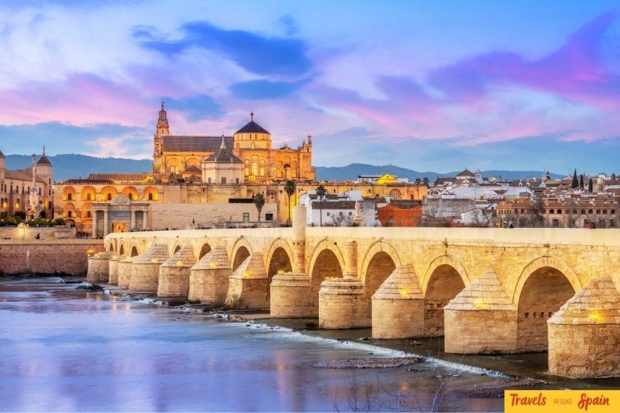 View of Córdoba’s historic Roman Bridge with the Mezquita illuminated in the background at dusk, a must-visit site and one of the best places to visit in Spain for first-time travelers.