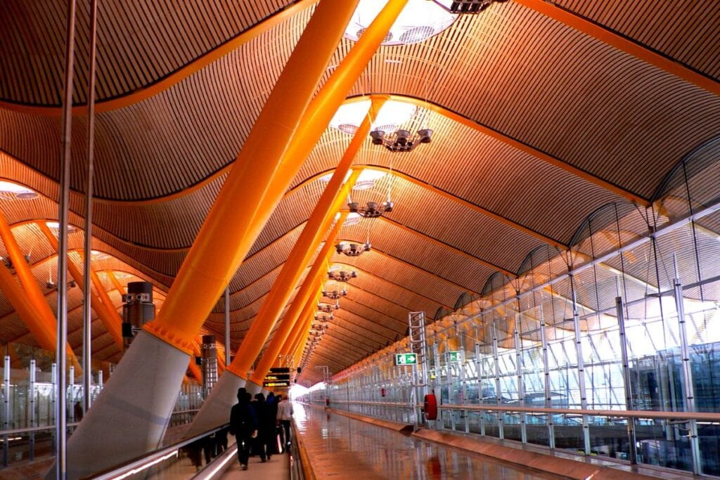 Interior of Madrid-Barajas Airport Terminal 4 with modern design and travellers.