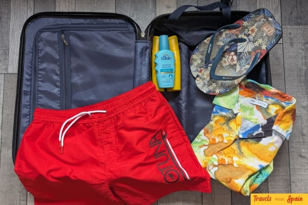 Open suitcase showing what to pack for Gran Canaria in June - organized compartments with swimwear, sunscreen, clothing and sandals.