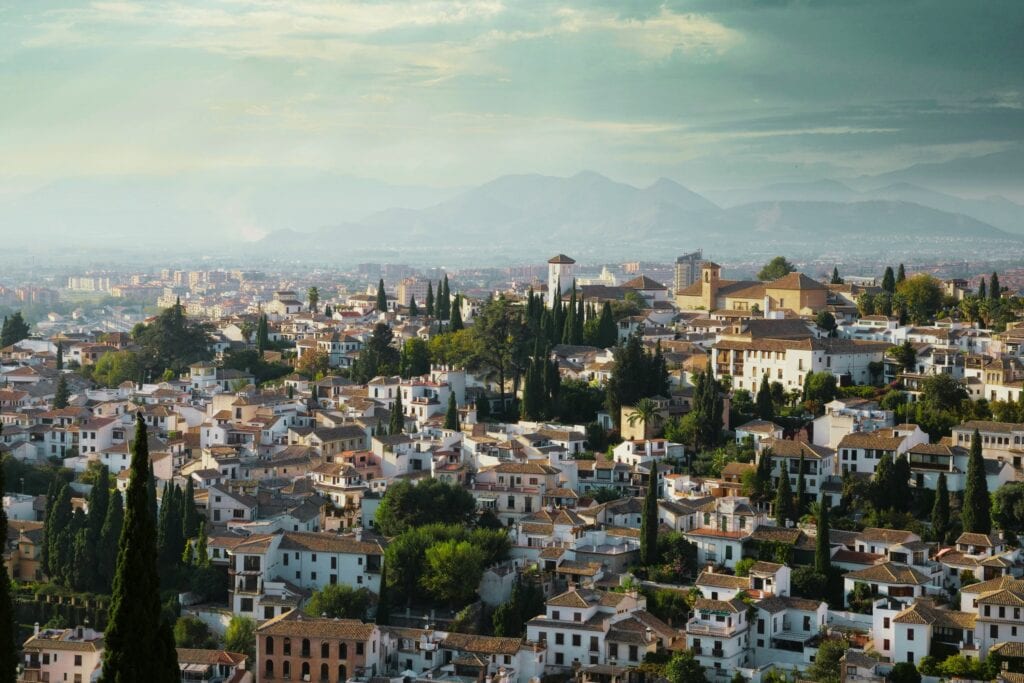 Aerial view of Granada, Spain, showing clusters of whitewashed houses stretching toward the distant mountains — a breathtaking perspective to inspire your search for where to stay in Granada, Spain.