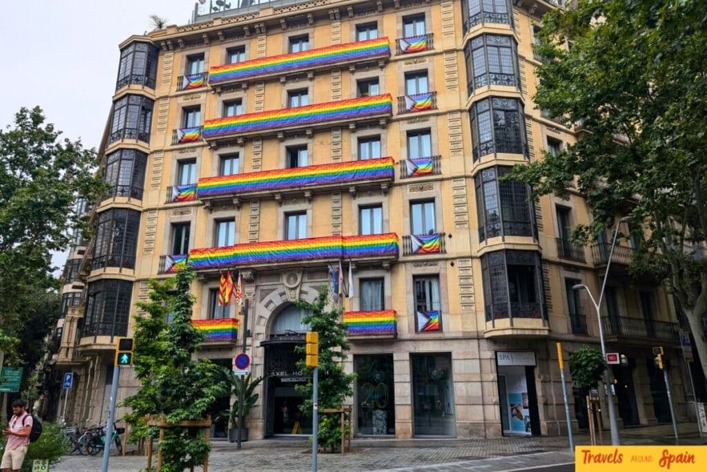 Axel Hotel Barcelona building with multiple rainbow Pride flags hanging from balconies in Eixample