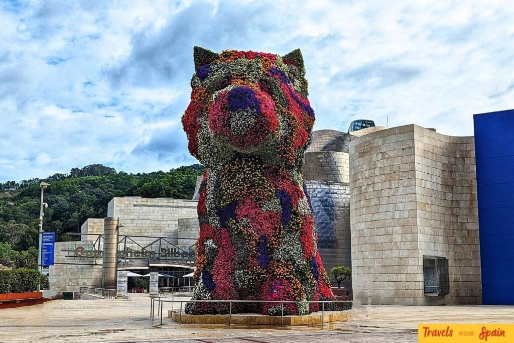 Guggenheim Museum Bilbao with large colorful flower puppy sculpture in foreground