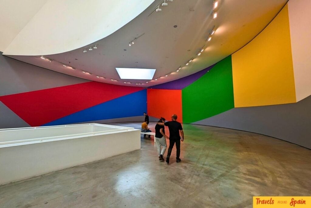 Colourful rainbow wall art installation in curved gallery space at Guggenheim Bilbao