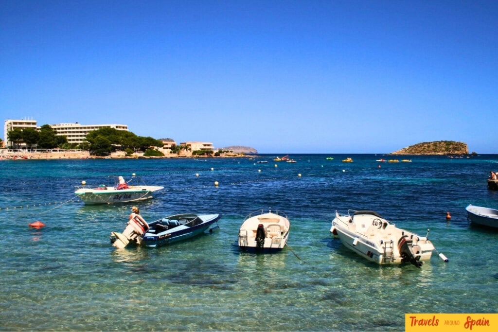 Ibiza crystal clear Mediterranean waters with boats showing beautiful coastline destination for Valencia to Ibiza travellers.