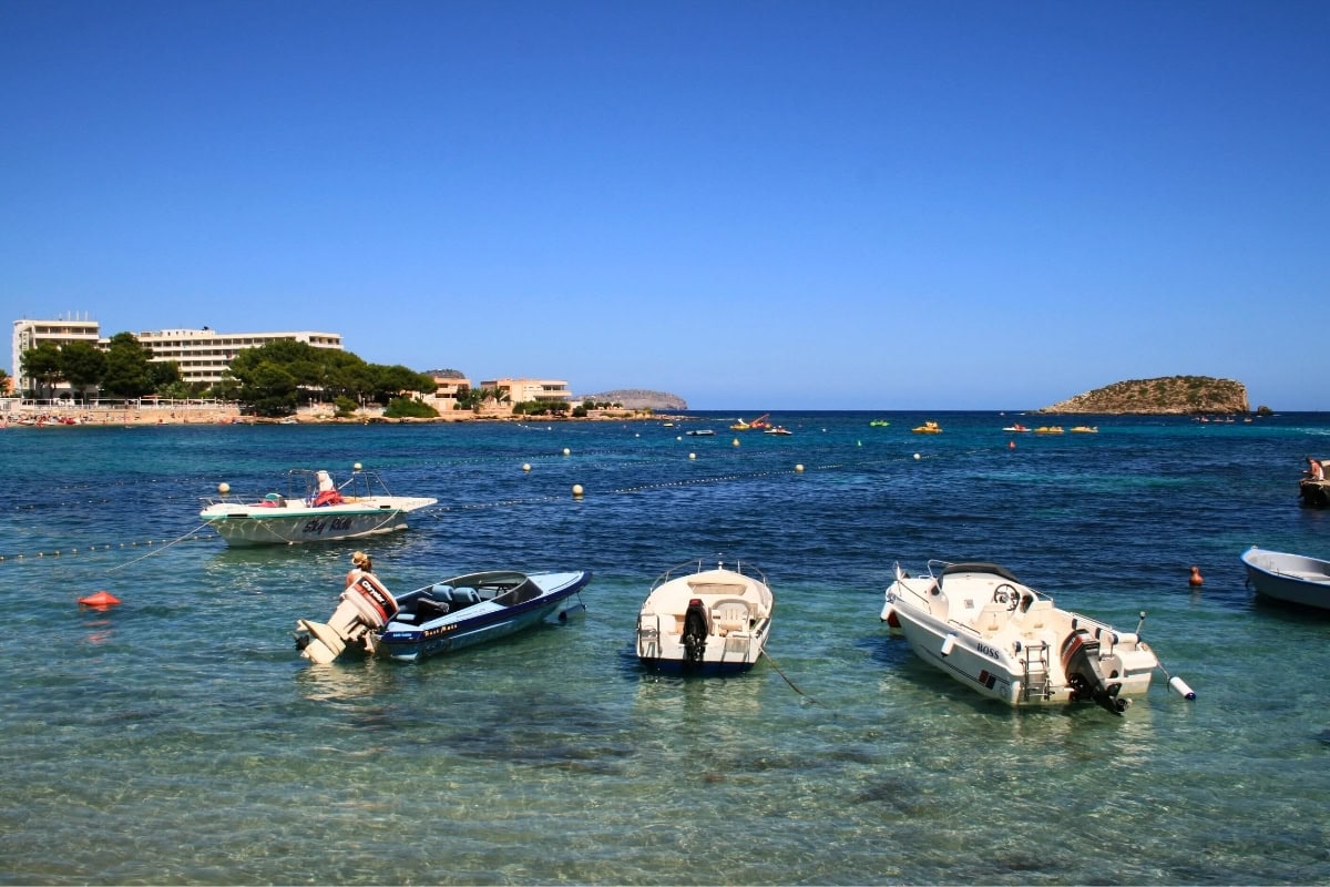 Es Canar - secluded bay with fishing boat and pine coastline