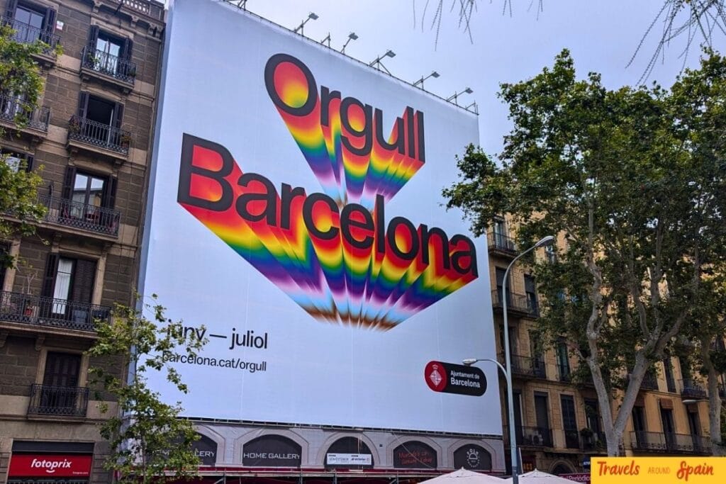 Large billboard advertising Orgull Barcelona Pride with colorful rainbow graphics and text