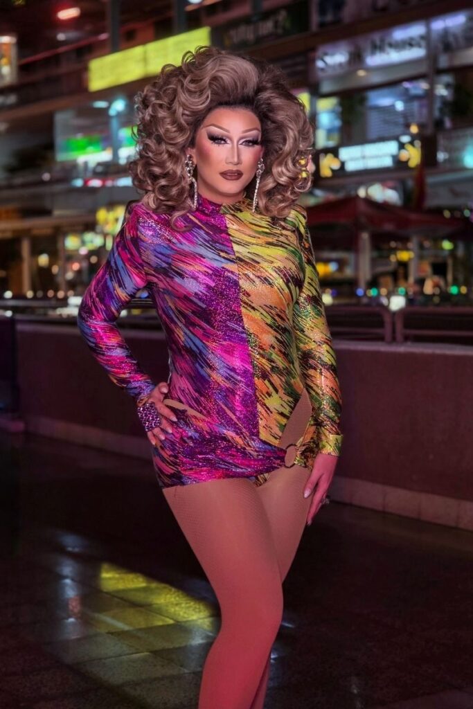 Reina Fame drag queen in vibrant rainbow metallic dress with voluminous blonde curls at Sparkles Bar Maspalomas