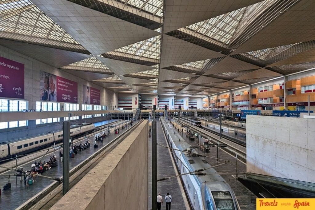 Interior of modern Spanish train station with high-speed trains and passengers
