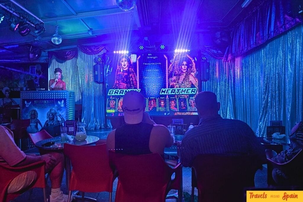 Sparkles Bar Maspalomas stage view during live drag performance showing curtains, lighting and intimate audience seating.