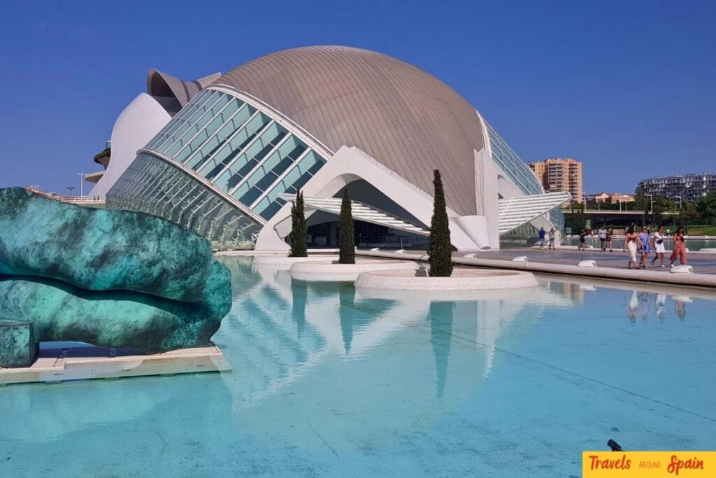Modern white curved shell-like architecture of the Palau de les Arts opera house in Valencia with blue water reflections