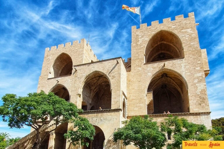Medieval stone towers of Valencia's Serranos Gates with Gothic arches and defensive architecture against blue sky.