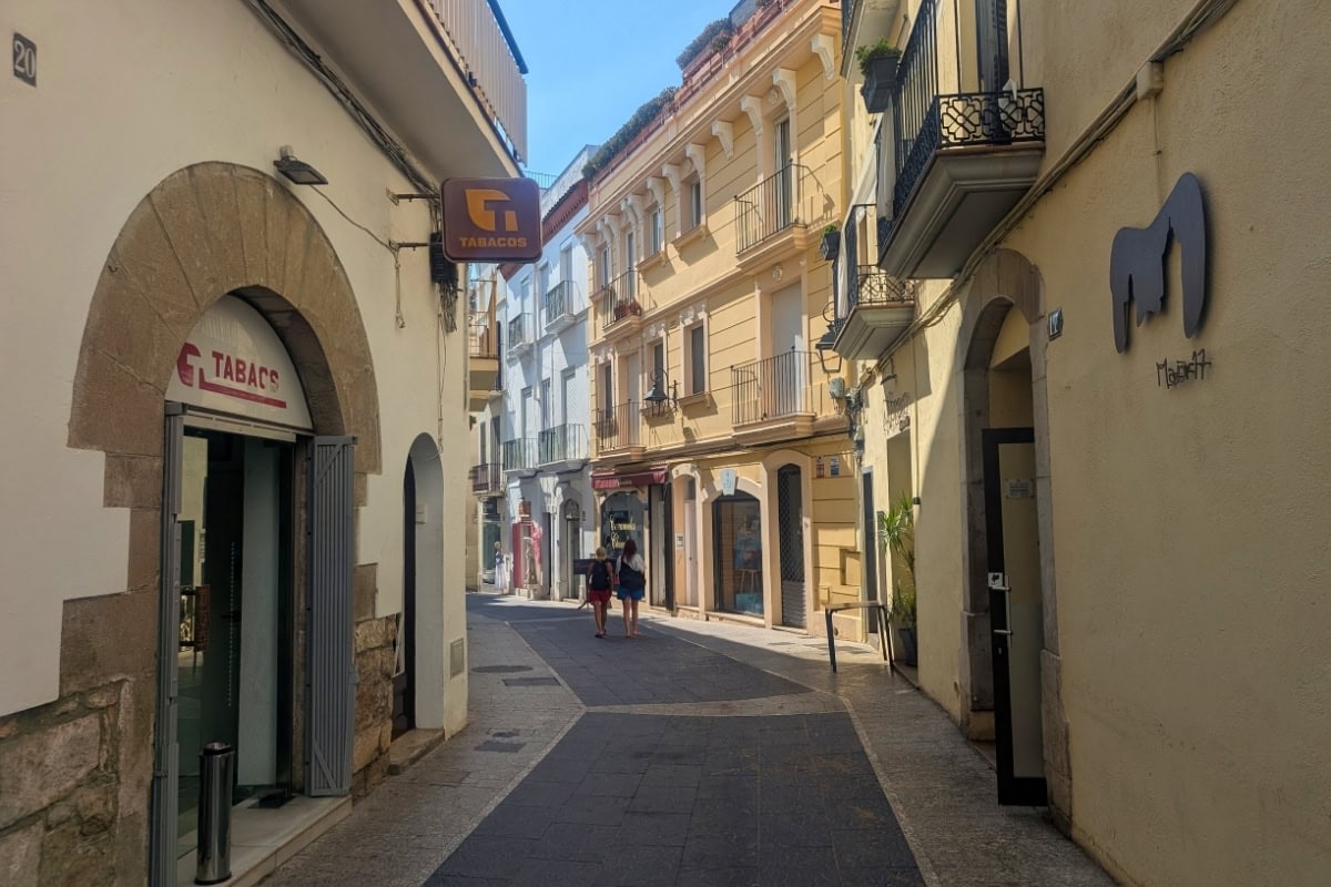 Narrow cobblestone street in Sitges historic quarter with traditional Catalan architecture and balconies