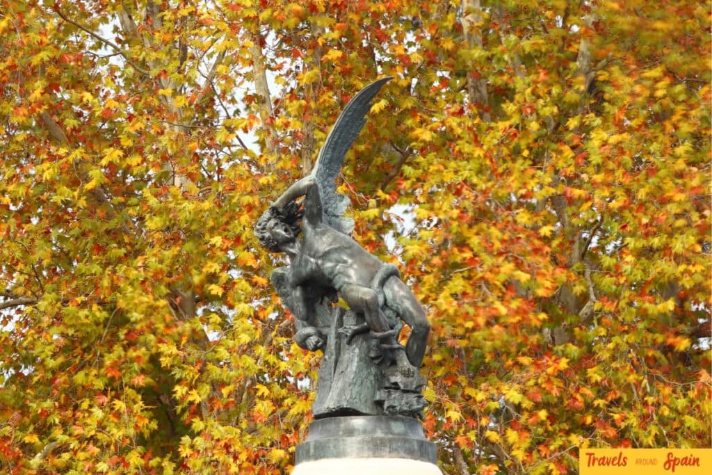 Statue of The Fallen Angel surrounded by autumn leaves in Parque Retiro in Madrid, Spain