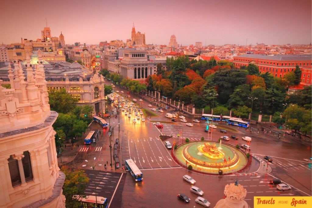 Aerial view of Madrid in October at sunset with autumn trees and city lights around the Cibeles Fountain
