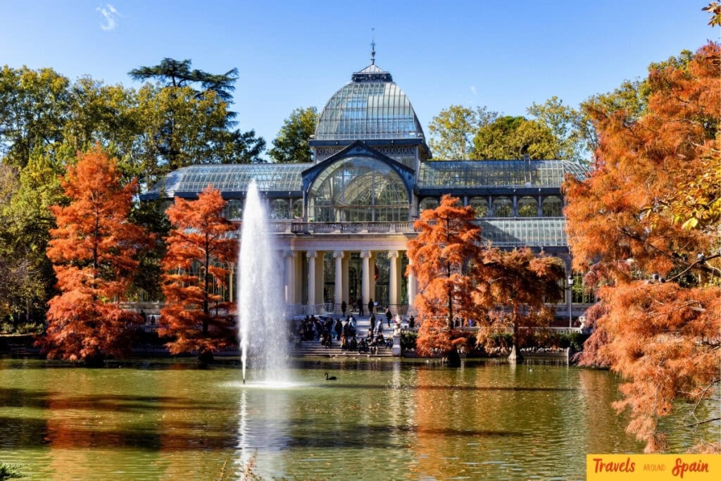 Retiro Park lake and Crystal Palace surrounded by autumn leaves in Madrid