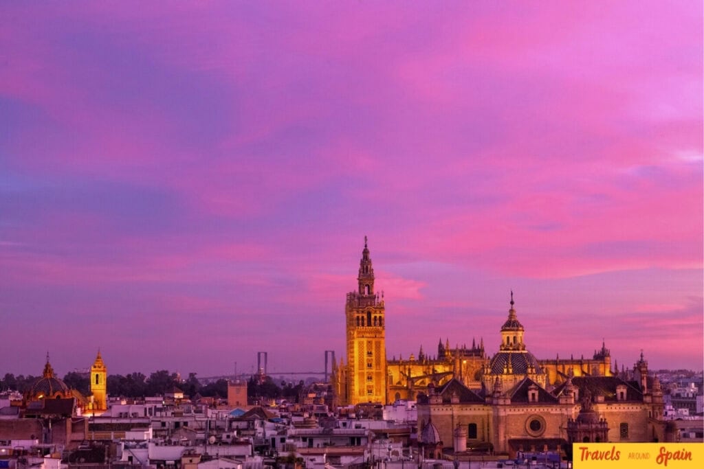 Seville Cathedral and Giralda tower at sunset with pink skies in October.