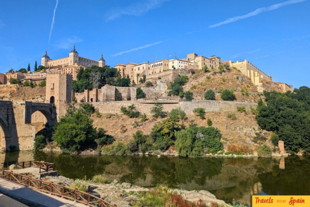View of Toledo’s Alcázar and medieval walls reflected in the Tagus River on a sunny October day.