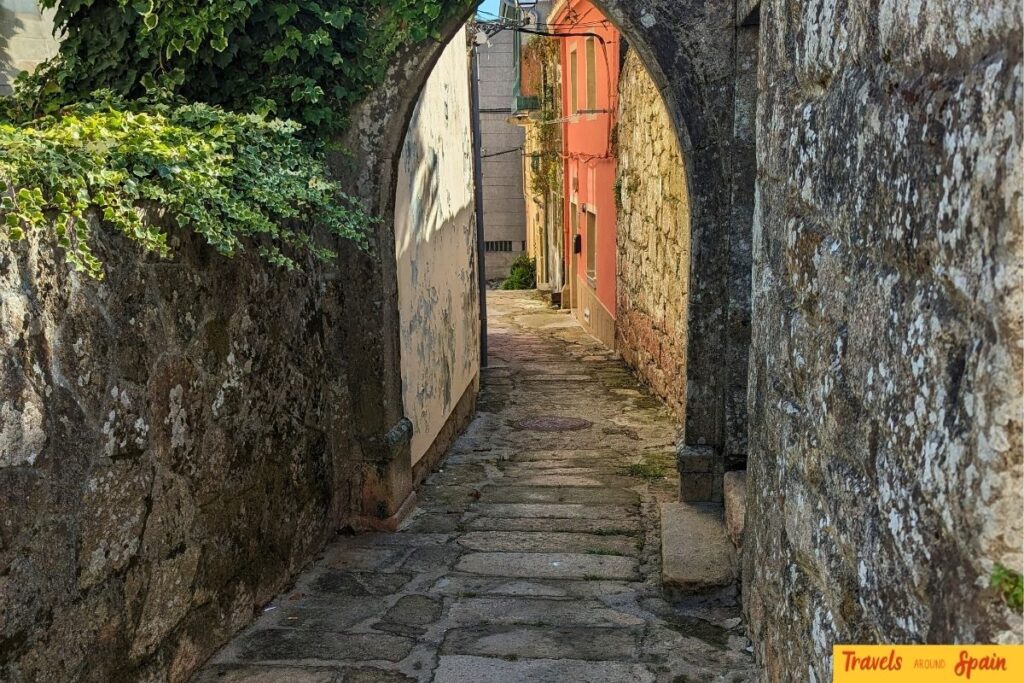 Narrow cobbled street in Spain with uneven stone pavement.